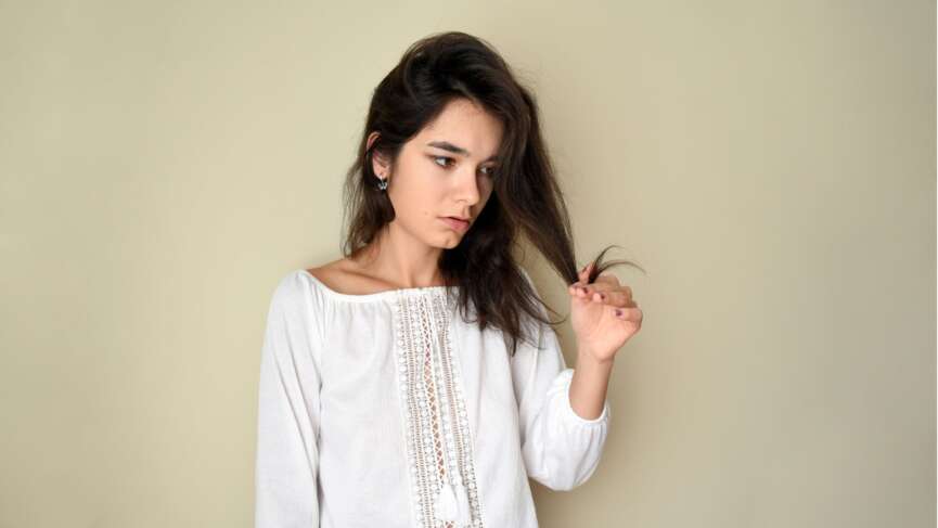 A woman hands holding dry, damaged hair ends. How to find hair porosity concept