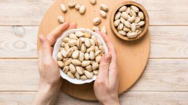 pistachios health benefits concept where a girl holding a bowl full of pistachios