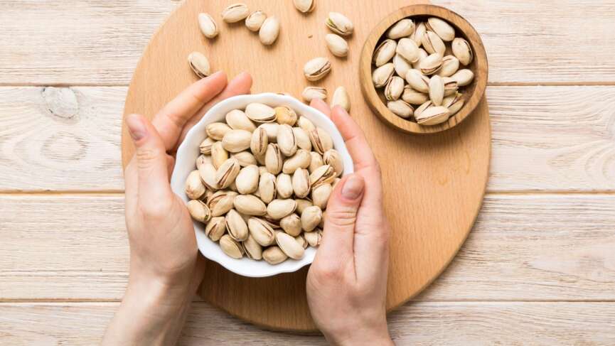 pistachios health benefits concept where a girl holding a bowl full of pistachios