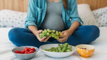 A pregnant woman eating nutritional fruits in bed, representing best foods for fertility