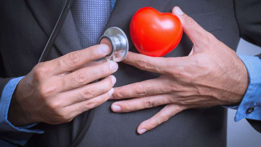 A doctor holding her hand on her chest with a stethoscope and heart model, representing common misconceptions of heart health