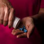 man pouring painkillers pills from bottle into hand