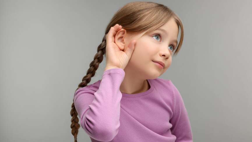 Little girl with hand near ear with hearing loss problem concept