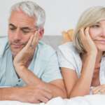 Close-up of displeased mature couple lying in bed, concept - low libido afer menopause