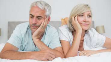 Close-up of displeased mature couple lying in bed, concept - low libido afer menopause