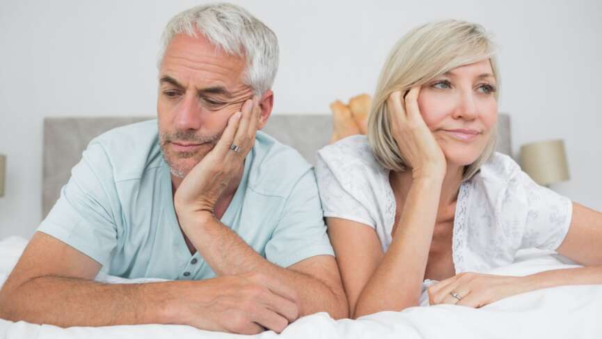 Close-up of displeased mature couple lying in bed, concept - low libido afer menopause