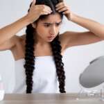 A girl checking her scalp in front of the mirror