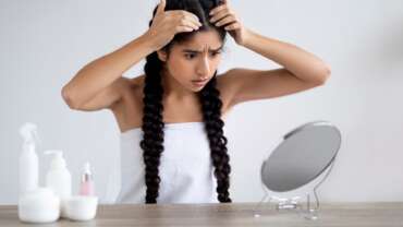 A girl checking her scalp in front of the mirror