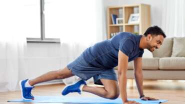 A man is doing running plank exercise at home following weekly recommended workout