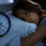 A depressed young girl lying in bed cannot sleep. Concept of teen sleep deprivation