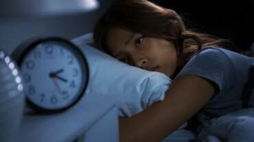 A depressed young girl lying in bed cannot sleep. Concept of teen sleep deprivation