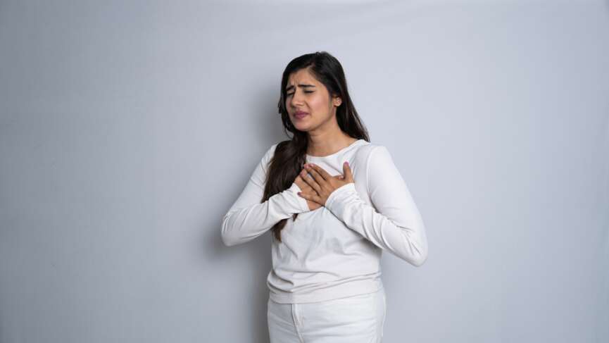 Portrait of an asian indian woman having a heart attack isolated on a white background. heart failure in women concept